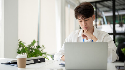 A focused aAsian businessman is working on his business work at his desk in a modern office.