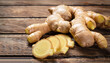 Whole root of fresh ginger and some slices on rustic wooden background. Warm tone