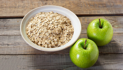 Wall Mural - Rolled oats in bowl and two green apples on rustic wooden surface. Copy space