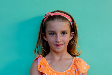 Portrait of happy caucasian schoolgirl with band over blue background at elementary school