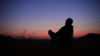 Wall Mural - man looking at the starry skies, crescent moon and shooting star in blue hour twilight time.