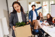 © Mediteraneo - Business woman carrying packing up all her personal belongings and files into a brown cardboard box to resign in the modern office, resign concept.