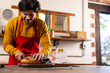© Wavebreak Media - Indian man in apron cutting bread in kitchen, copy space