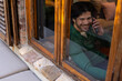 © Wavebreak Media - Happy indian man sitting by window and talking on smartphone at home, copy space