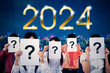 © Creativa Images - Group of business people covering their face with question mark in the paper while standing with 2024 number