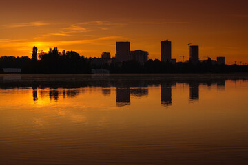 Wall Mural - Bucharest at sunrise. beautiful morning orange sky landscape of the city skyline and its reflection in Herastrau Lake. Travel to Romania.