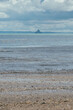 © Raquel - Fotografía vertical de Mont Saint Michel desde la distancia en el medio del océano, Francia.