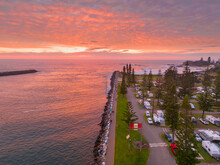 Aerial View Over A Riverside Caravan Park And Breakwater Under A Vivid Red Sunrise
