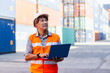 © eakgrungenerd - Foreman in uniform wearing safety helmet using laptop checking containers loading. Area logistics import export and shipping cargo freight ship.
