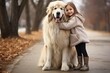 © Stavros - Little girl embracing her best frirng, a big dog, during outdoor walk. Love to pets concept. They standing together and looking at camera.