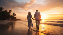 Old Couple Walking Hand In Hand On A Tropical Beach At Sunset