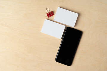 Poster - Mock up of blank business card and black smartphone screen on table