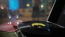 Vintage Turntable With A Spinning Vinyl Record Close Up On A Blurred Background Of A Couple Dancing A Slow Dance. Romantic Evening Of A Couple In Love, A Date. HDR BT2020 HLG Material.