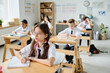 © AnnaStills - Group of school children sitting at desks during lesson, they studying in school