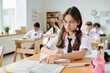 © AnnaStills - Schoolgirl sitting at her desk and reading textbook during lesson in school