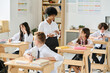 © AnnaStills - African American teacher talking to pupils at lesson at school