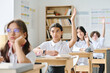 © AnnaStills - Schoolgirl sitting at her desk and raising her arm, she answering at lesson at school