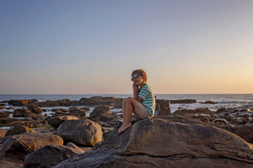 Canvas Print - Happy children, enjoying sunset over the ocean with their family, rocky beach