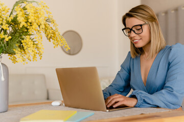 young pretty stylish woman working remote at home at table workplace, student education