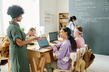 African American teacher explaining material to students during IT lesson