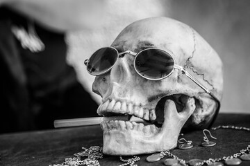 Black and white of human skull, wearing a pair of sunglasses