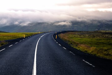 Poster - Scenic winding country road in a picturesque valley surrounded by majestic mountain peaks in Iceland