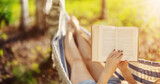 Fototapeta  - Woman lying in the hammock and reading an interesting book.