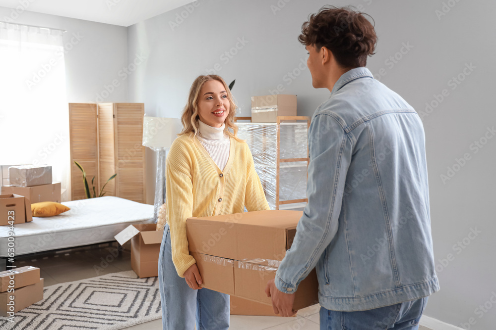 Young couple carrying box in bedroom on moving day