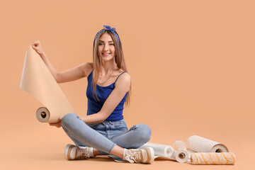 Wall Mural - Young woman with wallpaper roll sitting on beige background