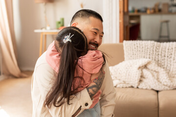 Wall Mural - Joyful Asian Dad Hugs His Kid Daughter At Living Room