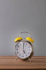 Wall Mural - Retro silver alarm clock. 5:00.  am,  pm. Neutral background. Brown wood surface. Vertical photography with empty space for text or image.