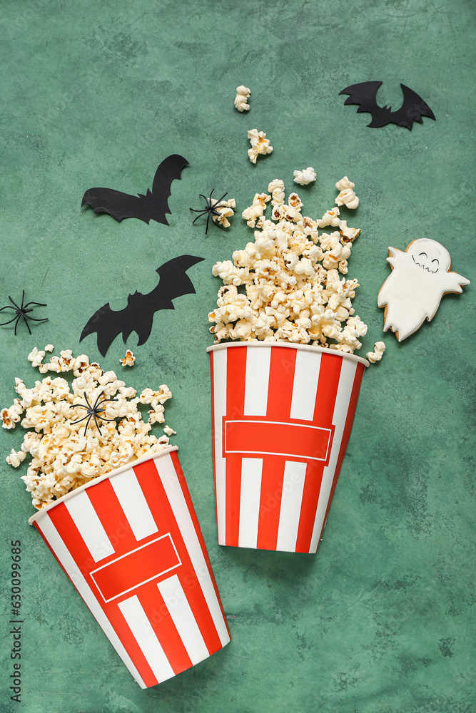 Composition with tasty popcorn, cookie and paper bats on green background. Halloween celebration