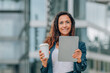 © carballo - middle age businesswoman with digital tablet or device and cup of coffee with office buildings background