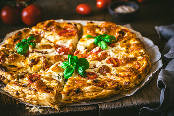 Wall Mural - Whole tomato quiche with basil on wooden background