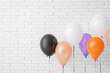 © Pixel-Shot - Different Halloween balloons near light brick wall in room