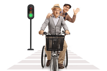 Wall Mural - Two elderly men riding on a tricycle towards camera at pedestrian crosswalk