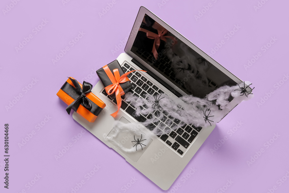 Composition with modern laptop, web and gift boxes for Halloween on purple background