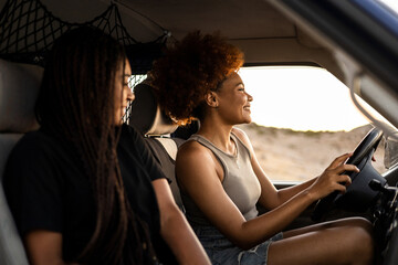 Two dark-skinned girls are driving a camper van to go on vacation. The woman with the afro hair drives the car while the girl with the braided hair is the co-pilot.Travel to the mountain.