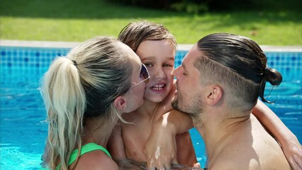 Poster - Mother with father and son resting and swimming in a pool in summer, happy family kissing