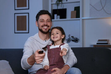 Canvas Print - Happy father and daughter at home. Man changing TV channels with remote control