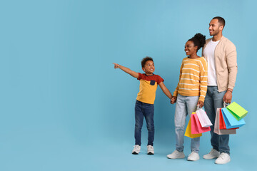 Wall Mural - Family shopping. Happy parents and son with colorful bags on light blue background, space for text
