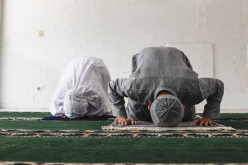 Front view of religious muslim couple praying together at home doing sujud movement called a Sajdah or prostration