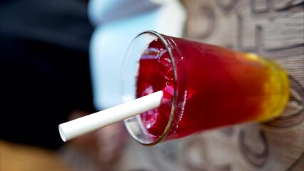 Wall Mural - Red bubble tea with boba in a glass with ice and big white straw close up slow motion, vertical screen