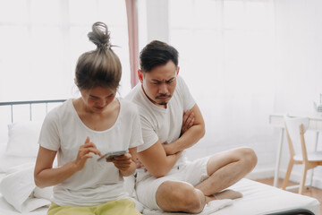 Wall Mural - Asian husband peeking wife chatting on the phone if she might has an affair.