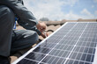 © DragonImages - Closeup image of builder installing solar panel on roof