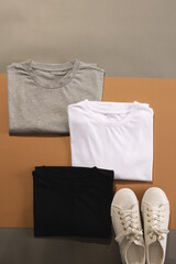 Close up of folded t shirts and white sneakers and copy space on brown background