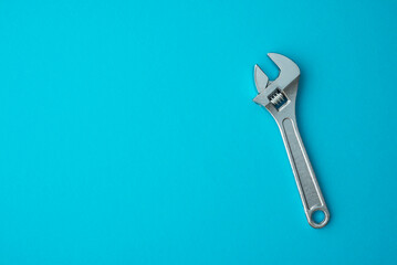 Chrome adjustable wrench on blue background copy space. Maintenance, repair, industry, manufacture factory, garage tool concept.