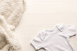 Flat lay of white baby grow and fur rug with copy space on white board background