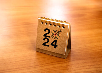 Wall Mural - Happy new year 2024 banner background. 2024 numbers year with target icon on beige small desk calendar cover standing on wood table, minimal style. Business goals plan and success concepts.