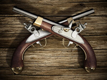 Crossed Flintlock Pistols On Old Wooden Background. 3D Illustration